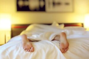 Füße einer in Bauchlage liegende Person auf einem Bett